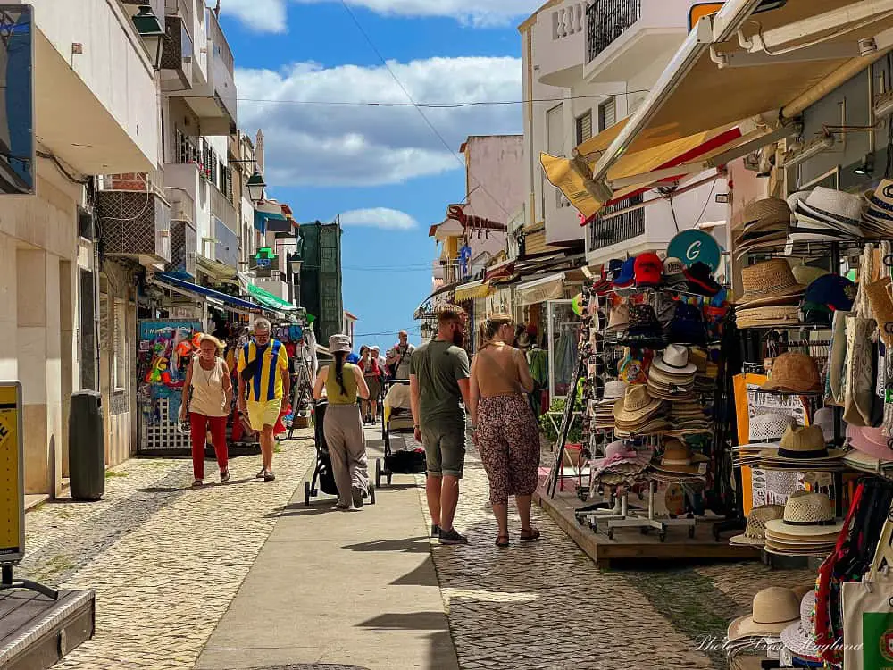 People walking in a street with shops in Alvor Town.