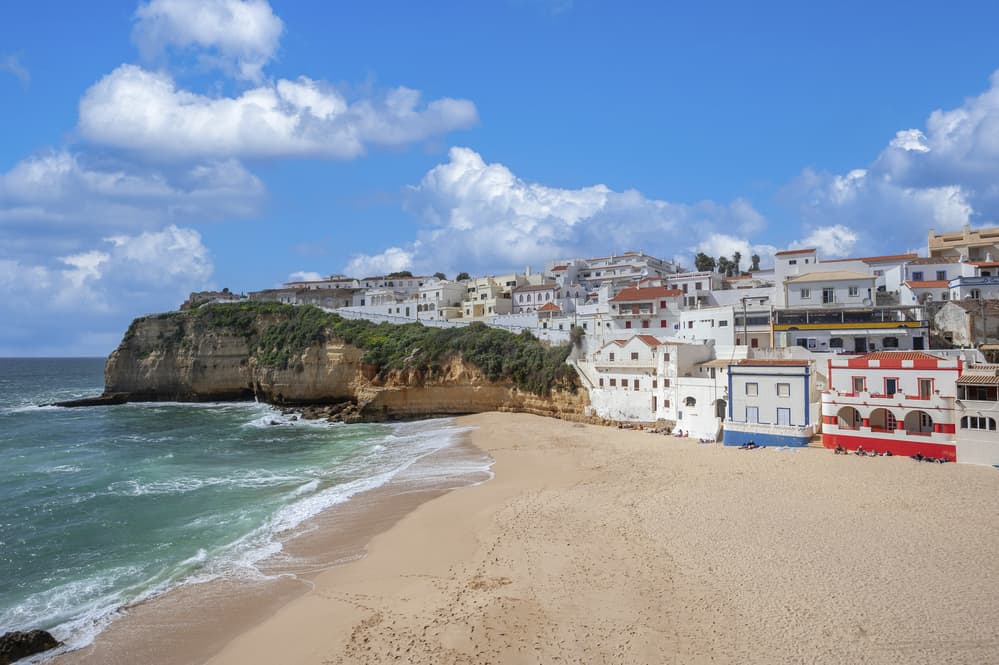 where to stay in Algarve for couples - Carvoeiro beach with white and colored houses leading to the beach