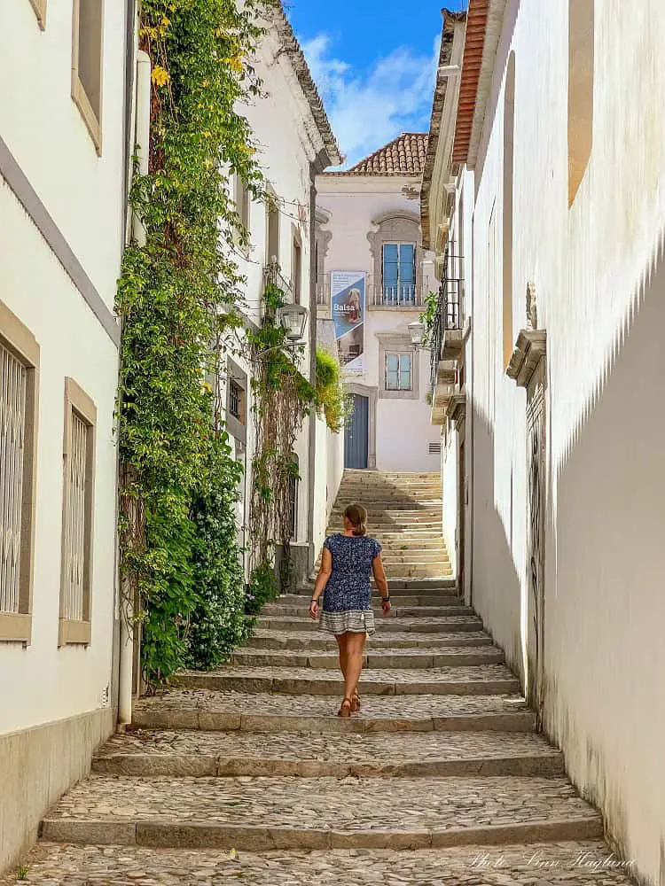 Me strolling through a narrow alley with stairs in Tavira Old Town which is one of the best things to do in on any Tavira itinerary.