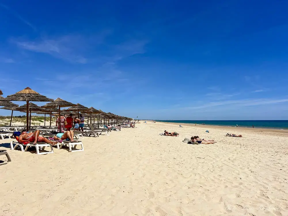 People sunbathing at Cabanas Beach, one of the best beaches in Tavira.